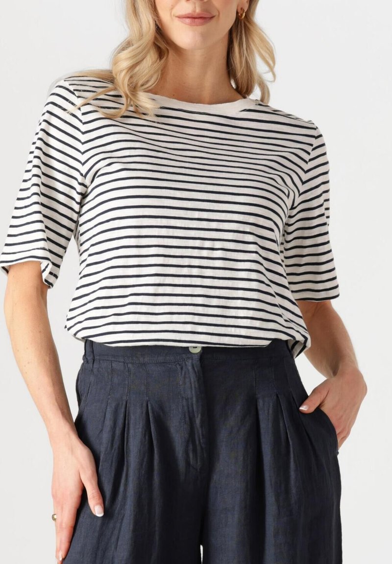 Gestreepte t-shirt in roomkleurig en marineblauw katoen, korte mouwen, relaxte pasvorm. Gecombineerd met marineblauwe geplooide linnen broek, met een knoopdetail.