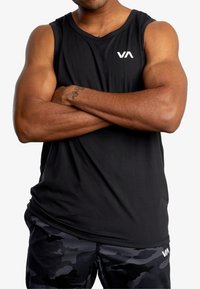 Schwarzes Sporttanktop mit rundem Halsausschnitt und Logo. Das Model kombiniert es mit shorts im Camouflage-Muster, die ein kontrastierendes Logo aufweisen.