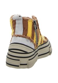 Brauner, pelziger High-Top-Sneaker mit gelben und grauen Textil-Akzenten, einem seitlichen Reißverschluss und einer dicken, gerillten Sohle mit schwarzen Streifen.