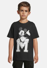 Černé bavlněné tričko s grafikou Mickey Mouse a velkým bílým "M" na přední straně. Krátké rukávy a kulatý výstřih.