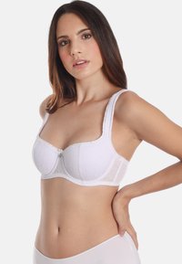 White lace bra featuring a structured underwire design, wide padded straps, scalloped edges, and a heart-shaped accent at the center.