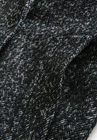 Tissu texturé gris et noir avec un motif en chevrons, présentant une apparence tissée douce et de subtiles variations de couleur.