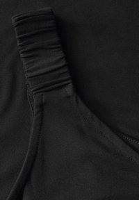 Tejido elástico negro con textura fruncida en un lado y acabado liso en el otro, mostrando detalles de costura y un diseño sin costuras.