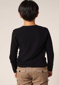 Zwarte lange mouwen shirt met een ronde halslijn, gemaakt van gebreide stof, gecombineerd met beige cargobroek met zakken en knoopdetails.