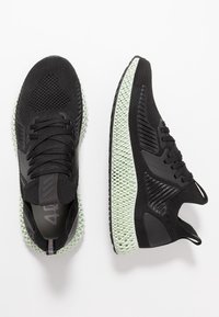 Zapatillas deportivas negras con una parte superior de malla transpirable y una entresuela de rejilla de color verde menta texturizada. Presenta cordones y acentos negros.