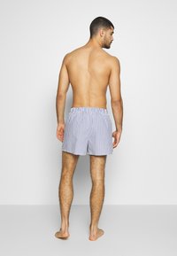 Calções de banho com riscas azuis e brancas, com um cós elástico e um corte descontraído, feitos de um tecido leve.