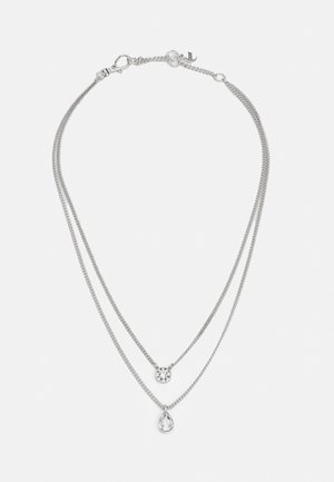 Double-layer silver necklace with a small round clear stone pendant on the shorter chain and a teardrop clear stone pendant on the longer chain.