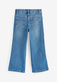 Jean flare en denim bleu clair avec taille haute, couture visible, deux poches arrière et un ourlet droit et propre.