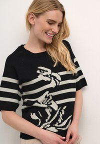 Sort og krem-stribet sweater med blomstermotiv. Den har korte ærmer og rund halsudskæring. Blød tekstur med en afslappet pasform.