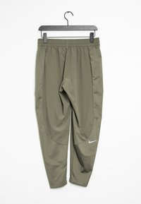 Pantaloni sportivi Nike verde oliva con cintura elastica, appesi a un gancio nero, con il logo Nike bianco vicino al ginocchio destro.