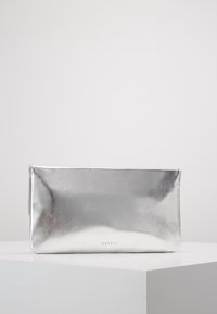 Pochette métallique argentée avec une texture lisse et un design minimaliste. Dotée d'une fermeture éclair et d'un logo embossé à la base.