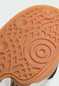 Gummisulor med ett orange texturmönster som har cirkulära och linjära mönster, övergår till en vit övre del.