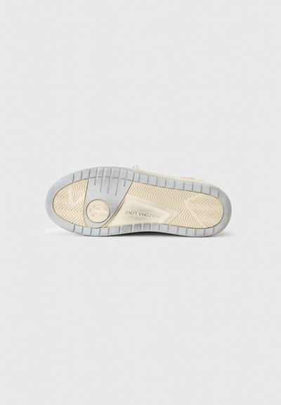 Σόλα μπεζ αθλητικού παπουτσιού με γκρι πέλμα, κυκλικό λογότυπο κοντά στη φτέρνα και κείμενο «ARIZONA LOVE» εγχάρακτο στο κέντρο.