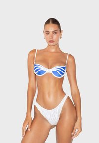 Set bikini con un top bianco decorato con motivi a onde blu, supporto con ferretto e spalline sottili; slip bikini bianco arricciato coordinato.