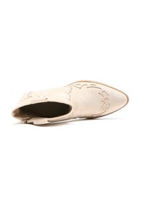 Stivale alla caviglia a punta in suede beige, con cuciture decorative e dettagli a taglio, tacco basso e chiusura con cerniera.