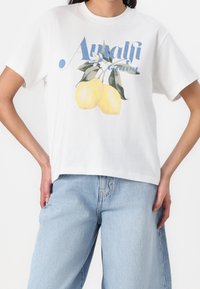 Camiseta de algodón blanca con un diseño gráfico de dos limones amarillos con hojas verdes y el texto "Costa de Amalfi" en letras azules.