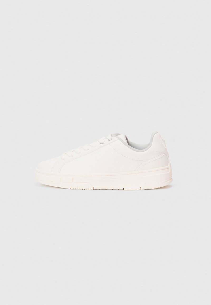 Sneaker bianco a basso profilo con lacci, upper liscio e suola texturizzata, mostrato di lato su uno sfondo neutro.