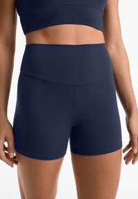 Marinblå idrottsshorts av mjukt, stretchigt tyg. Hög midja och minimalistisk design utan synliga mönster eller detaljer.