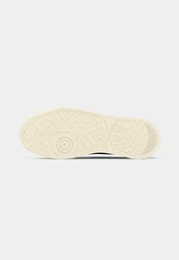 Μπεζ σόλα παπουτσιού με υφή για καλύτερη πρόσφυση, κυκλικός δείκτης μεγέθους με ένδειξη 37, το όνομα της μάρκας "GANT" και σχεδιασμός πέλματος με μοτίβα.