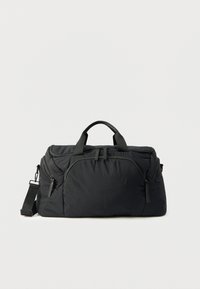 Μαύρη τσάντα duffel από ανθεκτικό ύφασμα με διπλές επάνω χειρολαβές, ρυθμιζόμενο ιμάντα ώμου και θήκες με φερμουάρ. Μαλακή υφή, ορθογώνιο σχήμα.