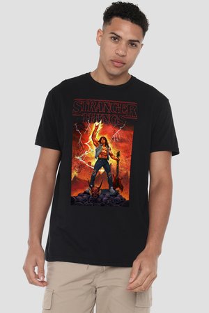 Young man wearing black Stranger Things T-shirt featuring a muscular character with guitar and lightning in a fiery background.