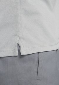 Vaaleanharmaa urheilupaita, jossa on huokoinen ja hengittävä kangas; helman sivuilla sivuhalkiot liikkuvuuden helpottamiseksi.