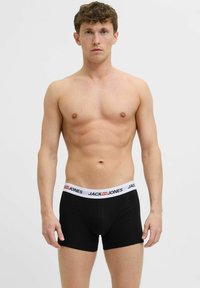 Crne bokserice od mekanog materijala s bijelim pojasom na kojem je u crvenoj boji oznaka "JACK & JONES". Klasični prilagođeni dizajn i dužina do sredine bedra.