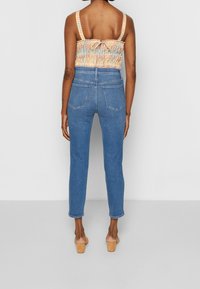 Modré džíny s vysokým pasem a hladkou dením texturou, s zadními kapsami a zúženými nohavicemi. Hlavní částí je kostkovaný smockovaný top s tenkými ramínky.