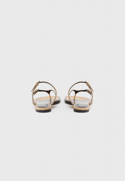 Καφέ δερμάτινα σανδάλια με λεπτό σχεδιασμό λουριού, πίσω κούμπωμα με αγκράφα, επίπεδη σόλα και λεία μπεζ εσωτερική σόλα.