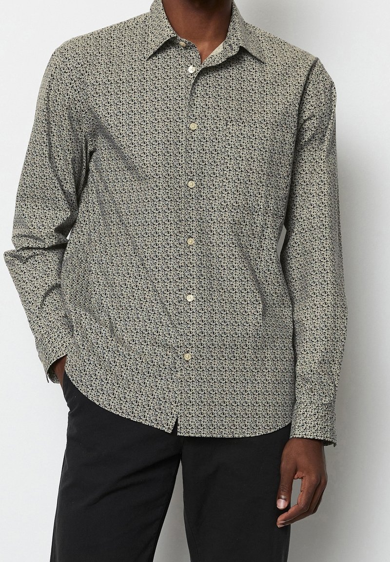 Lange mouwen shirt in lichtbeige met een donker patroon. Heeft een klassieke kraag, knopen aan de voorkant en een relaxte pasvorm. Textuurstof.