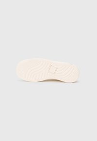 Talpa de sneaker din cauciuc de culoare crem, având un model texturat cu caneluri pentru aderență și un detaliu cu logo pătrat în centru.