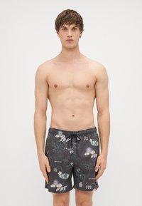 Čierne plavky s farebnými grafickými potlačami, elastickým pásom s sťahovacou šnúrkou a voľným strihom. Hladká textúra látky.