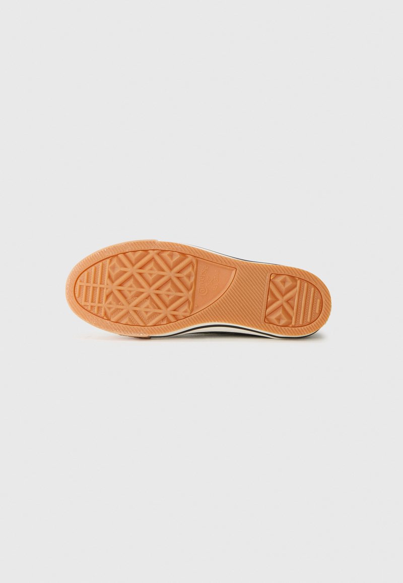 Semelle d'une sneaker Converse All Star noir et blanc avec un profil de caoutchouc orange texturé et des motifs géométriques.