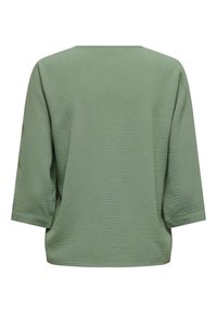 Haut ample à manches longues, vert clair texturé, avec un large col et un ourlet droit.