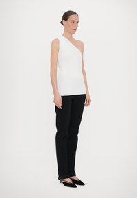Hvit, én- skulders ribbet topp kombinert med svarte bukser og svarte spisse hæler. Glatt tekstur, tettsittende design, minimalistisk stil.