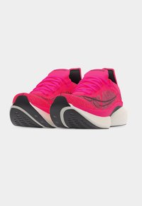 Φωτεινά ροζ αθλητικά παπούτσια Saucony με μαύρες και λευκές σόλες, πλεκτή υφή και κορδόνια, εμφανίζονται σε κεκλιμένη μπροστινή όψη σε λευκό φόντο.