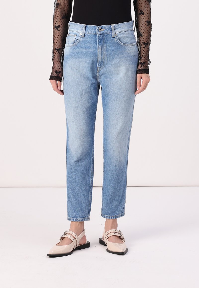 Vaqueros de mezclilla de un azul claro con un diseño de pierna recta, cintura alta y estilo clásico de cinco bolsillos. Llevados con zapatos de tacón abiertos en color beige.