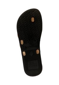 Suela de sandalia de goma negra con un patrón de agarre texturizado y tres pequeñas tachuelas color marrón claro. Presenta un logo y marcas en relieve en la superficie.