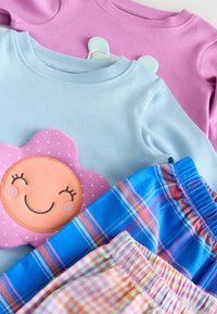 Du apsaugos ilgomis rankovėmis marškiniai: šviesiai mėlynas su rožine gėlių grafika ir levandų spalvos. Po jais, dvi poros šortų su languotais raštais ir elastingais juosmenimis.