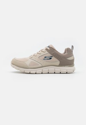 Scarpa sportiva beige con tomaia in rete, accenti sintetici lisci, suola testurizzata e linguetta. Presenta un logo sul lato e chiusura con lacci.