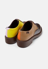Scarpe di pelle caratterizzate da una combinazione di colori: giallo, viola, marrone chiaro e arancione. Forma arrotondata con una suola spessa marrone e lacci a contrasto.
