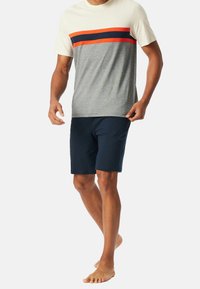 Grijze T-shirt met oranje en marineblauwe horizontale strepen op de borst, gecombineerd met marineblauwe shorts. Van katoen, casual pasvorm, zonder zichtbare merknaam.