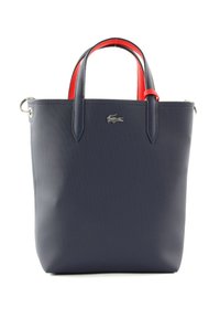 Sac fourre-tout bleu marine avec des poignées rouges, finition texturée, accessoires en métal argenté et un petit logo sur le devant. Design compact et structuré.