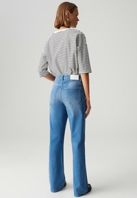 Gestreept oversized t-shirt met korte mouwen, gecombineerd met high-waisted blauwe jeans met zakken, een zachte denimtextuur en een lichte vervaging.