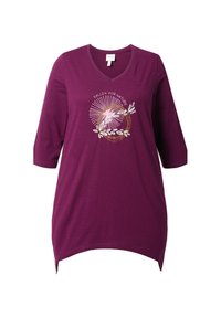 Lila Tunika mit V-Ausschnitt, drei Viertelärmeln und abgerundetem Saum. Sie weist ein florales und textliches Design in Weiß und Gold auf der Vorderseite auf.