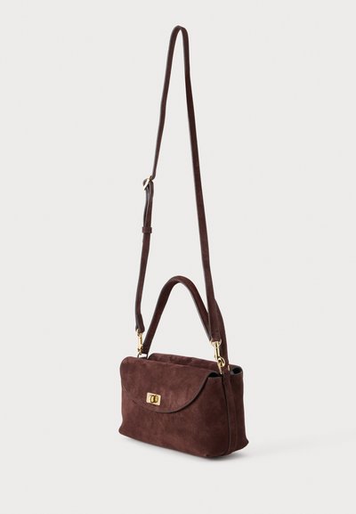 Sac à main en daim marron avec fermeture à rabat, fermoir doré, poignée courte et bandoulière longue réglable sur fond uni.