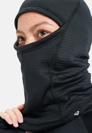 Schwarze Balaclava mit gerippter Textur, hohem Kragen und detaillierter Verarbeitung. Eingerahmt mit einem kleinen Markierungslabel an der Seite.