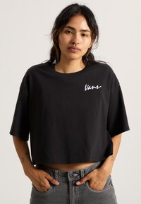 Mustat napitettu t-paita, joka on valmistettu puuvillasta, lyhyillä hihoilla ja pyöreällä kaula-aukolla. Rinnassa on valkoinen brodeerattu "Vans"-logo.