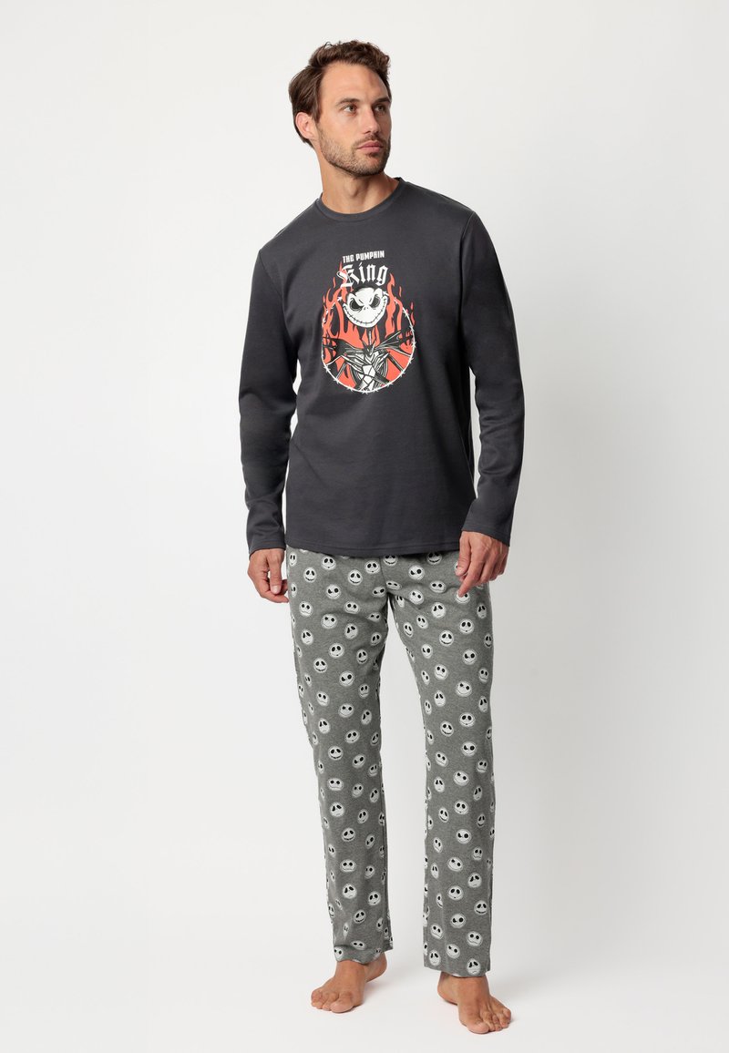 La camiseta de pijama de manga larga en gris presenta un gráfico colorido de una calavera y llamas. Los pantalones grises tienen un patrón de calaveras por toda la prenda.