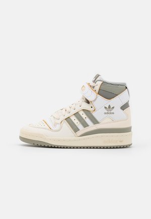 Baskets montantes Adidas en crème, blanc et olive avec les trois bandes caractéristiques, une bride à la cheville et une semelle en caoutchouc.
